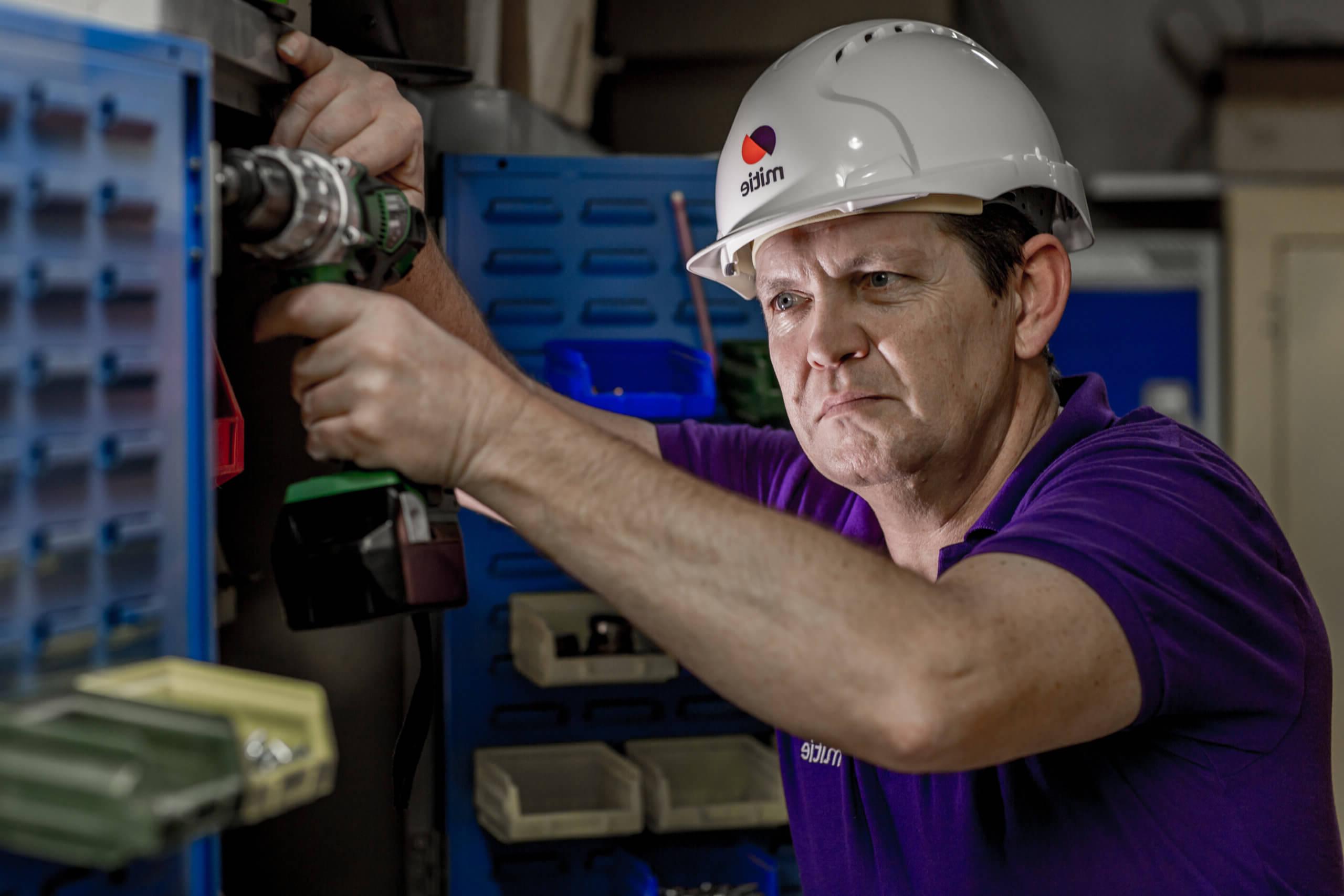 Mitie engineer operating a drill